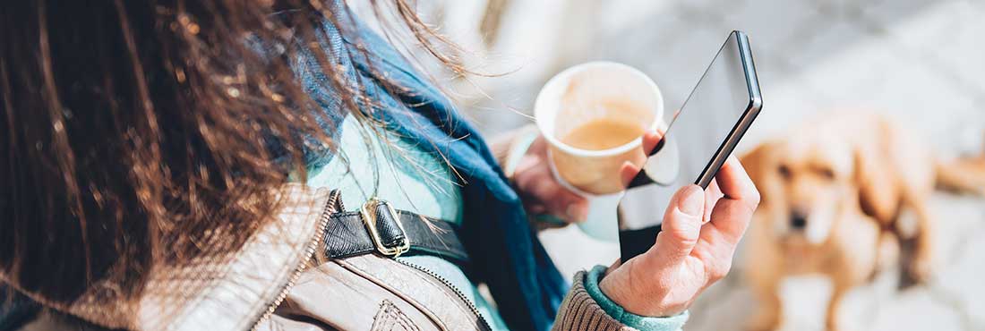 Woman holding a coffee and looking at her phone