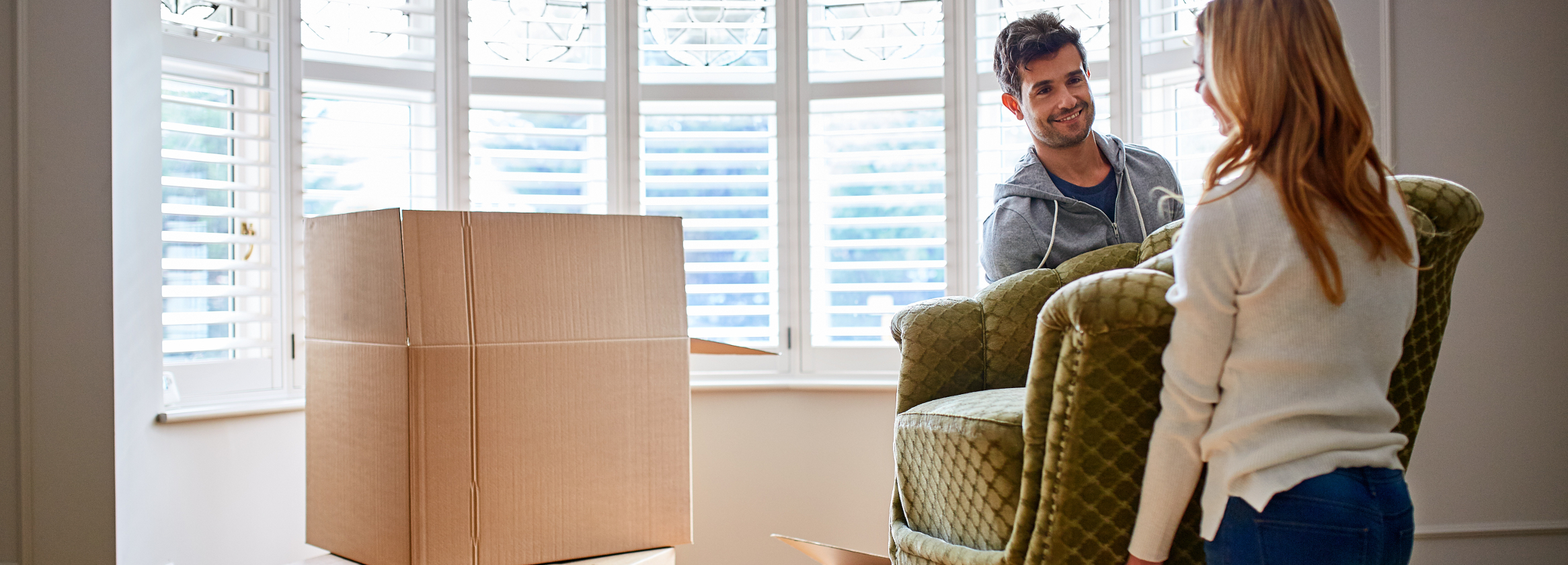 Couple moving furniture into the house